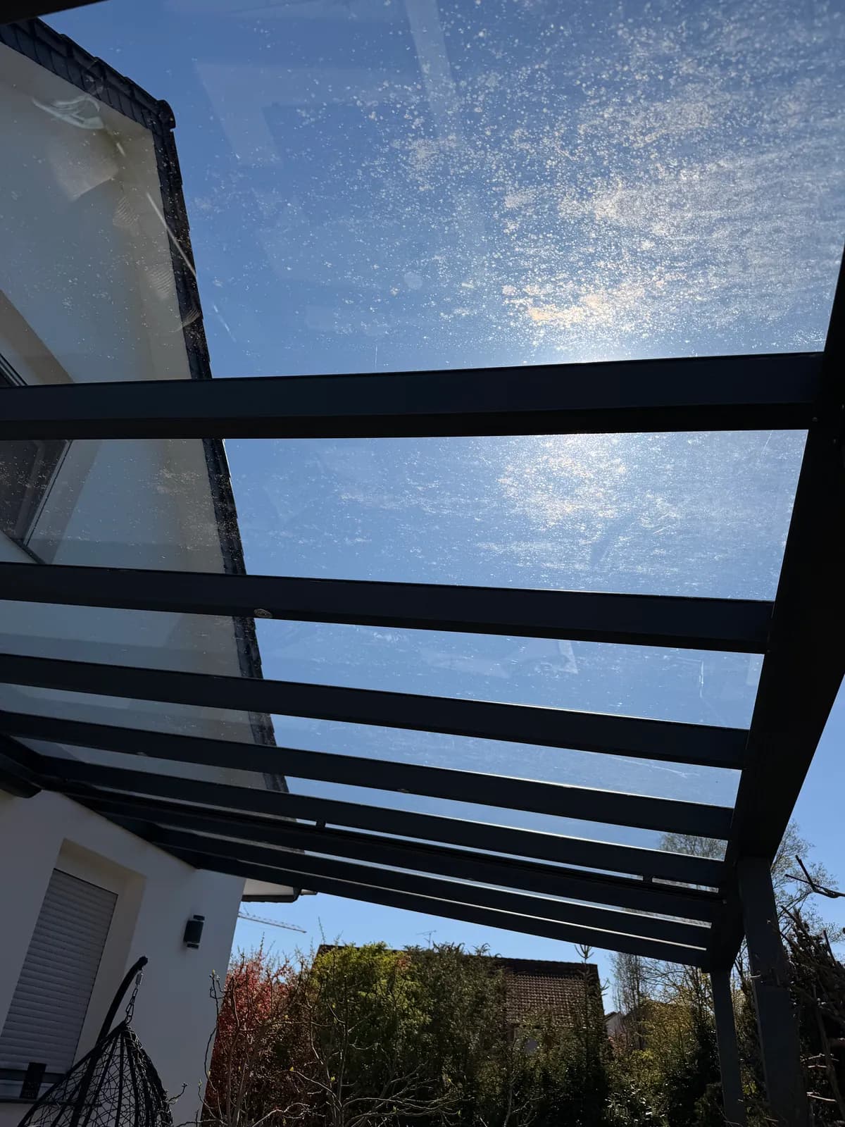 Glasdach einer Überdachung von unten mit verschmutzten Scheiben und Profilen